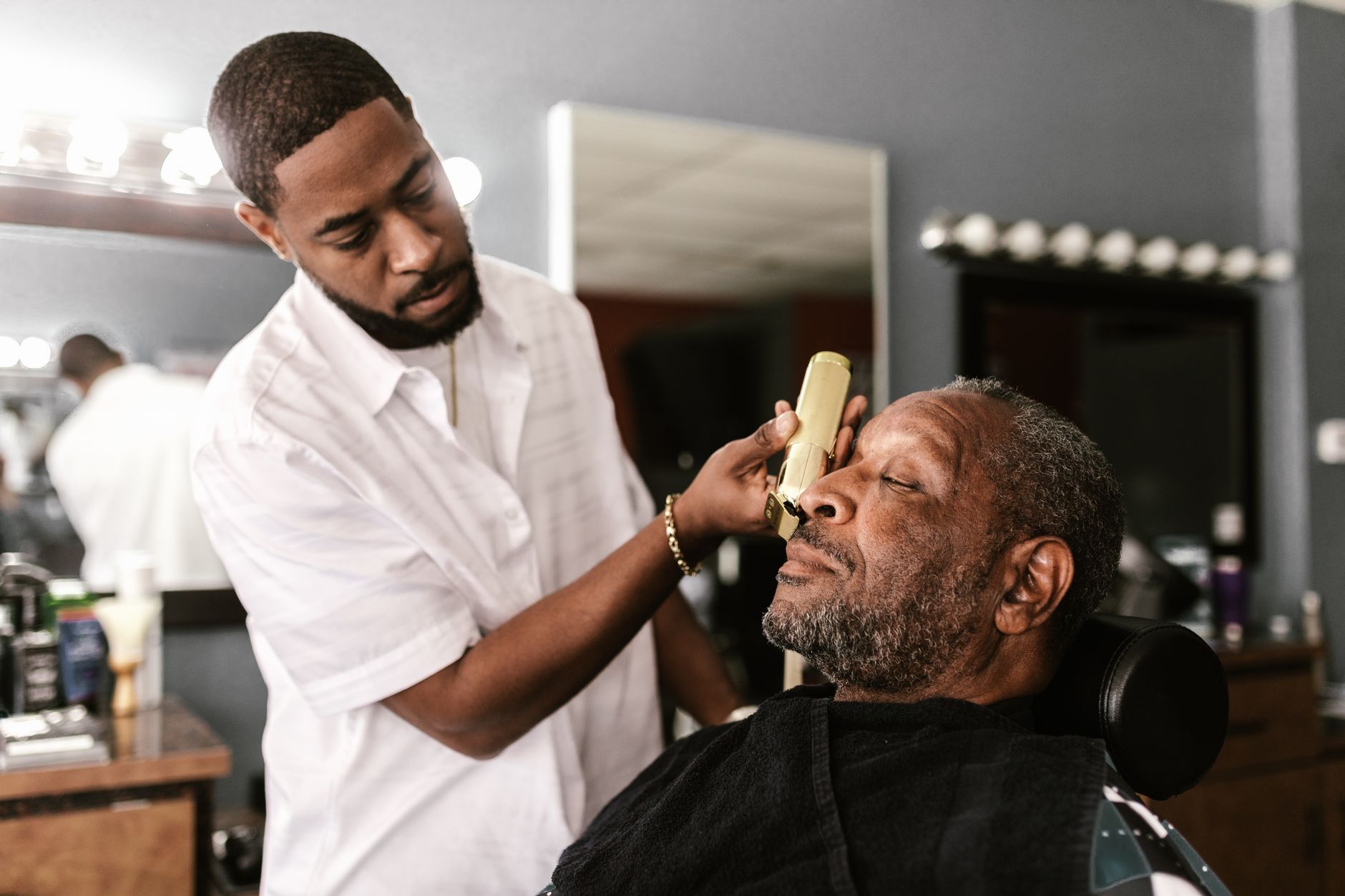 Barber stříhá klienta v salonu Mužský Střih, teplé světlo